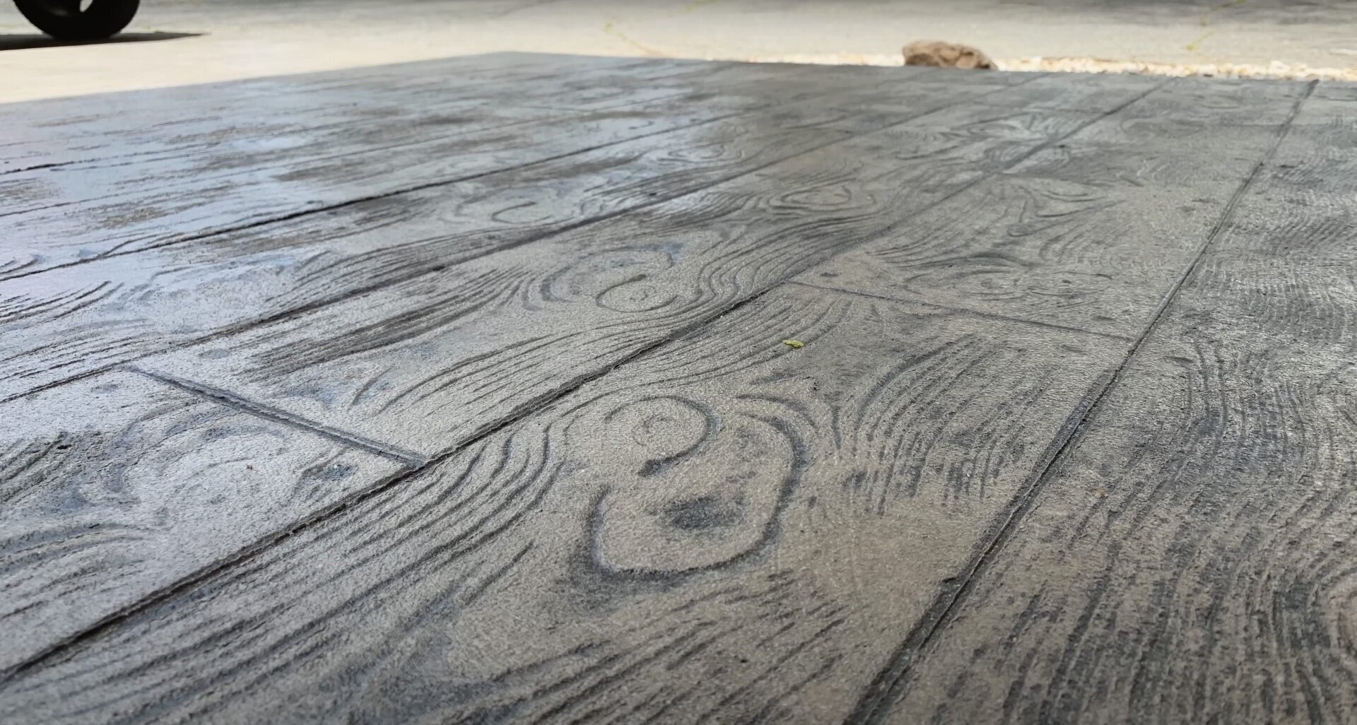 Stamped decorative concrete driveway installation with wood grain texture Detailed stamped concrete driveway with wood grain pattern showcasing decorative concrete craftsmanship